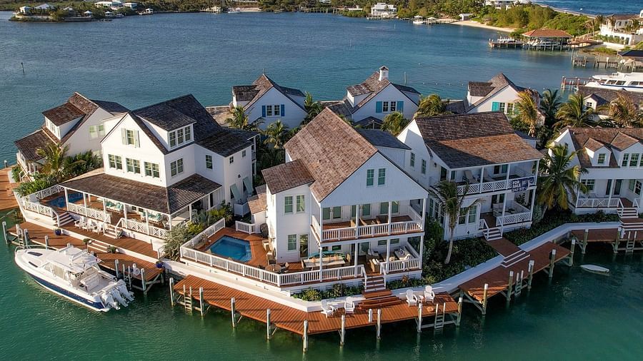 Aerial view of luxurious waterfront houses with private docs, swimming pools and a boat docked nearby at Abaco Inn.