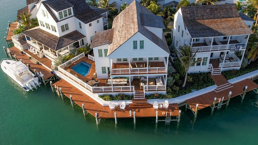 Aerial view of luxurious waterfront houses with private docs, swimming pools and a boat docked nearby at Abaco Inn.