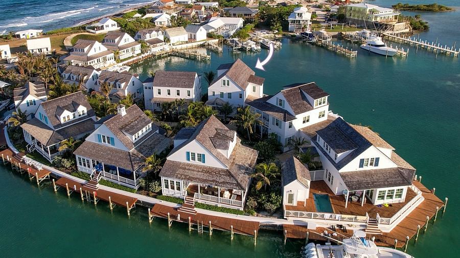 Aerial view of luxurious waterfront houses with private docs, swimming pools and a boat docked nearby at Abaco Inn.