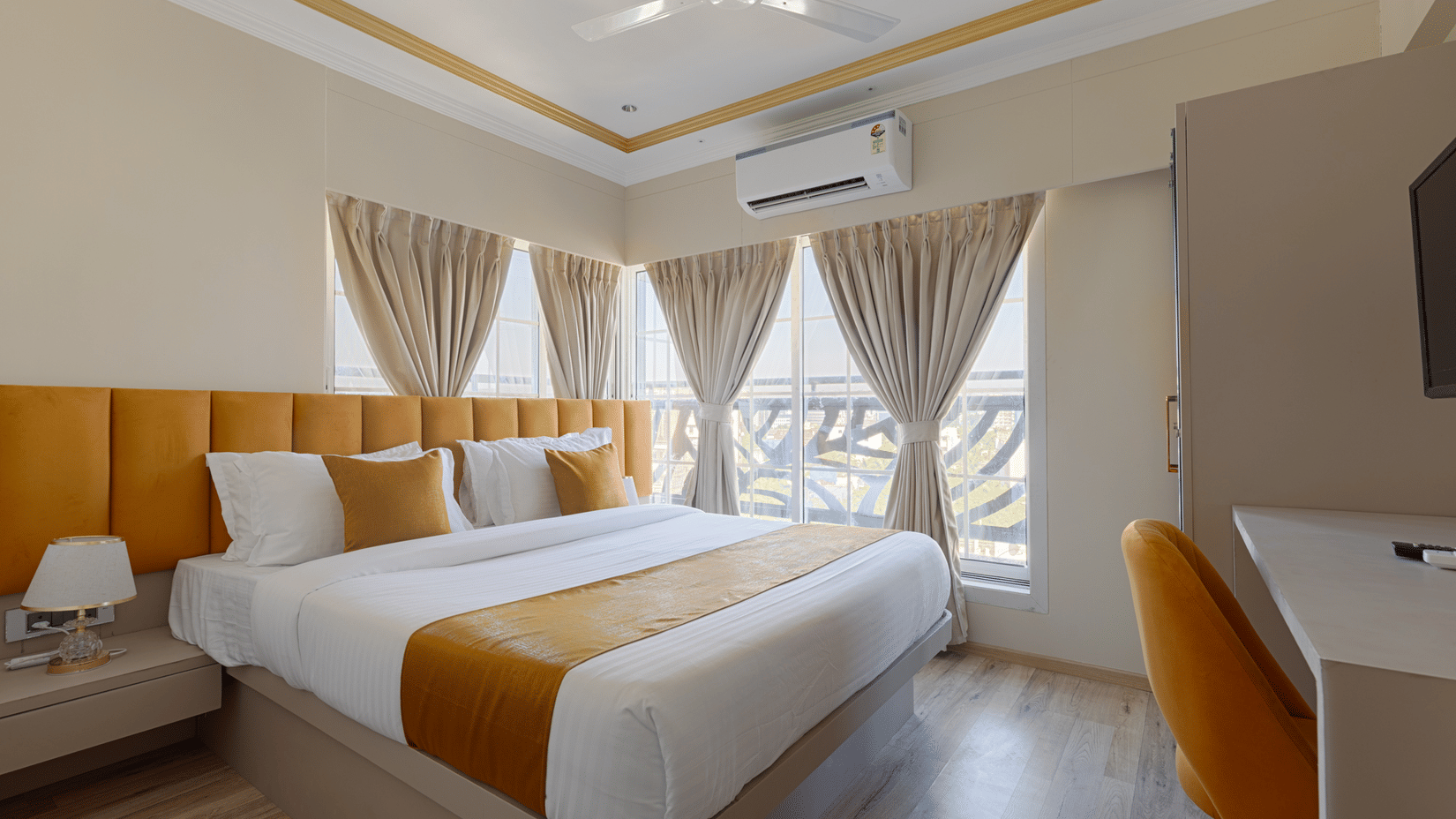 A sunny bedroom with large windows, light brown curtains, and a work desk - Home2 Residency, Mumbai Airport