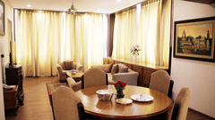 Well decorated room with round table and chairs along it, a sofa in the distance, a painting hung on the wall, and tall windows covered by curtains - Clarks Avadh, Lucknow