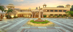Grand view of a palatial building with domes and a large courtyard at sunset - Heritage Village Resorts & Spa.