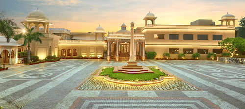 Grand view of a palatial building with domes and a large courtyard at sunset - Heritage Village Resorts & Spa.