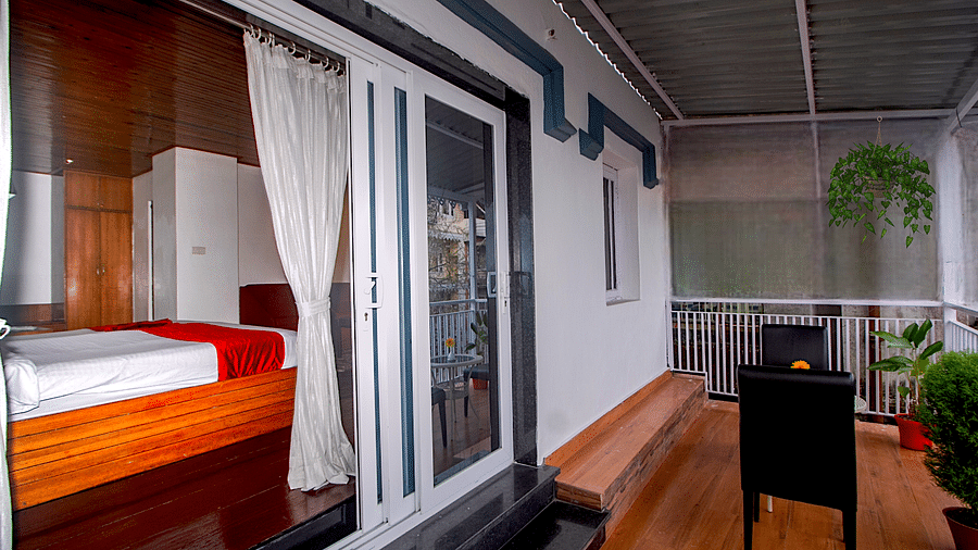 Outdoor balcony with wooden railings, potted plants, and a view of the surroundings.