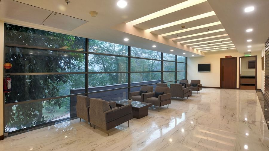 Modern lounge area with comfortable armchairs, large windows overlooking greenery, and a polished floor - Heritage Village Resorts & Spa.