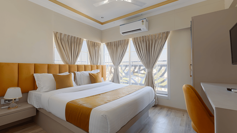 A sunny bedroom with large windows, light brown curtains, and a work desk - Home2 Residency, Mumbai Airport