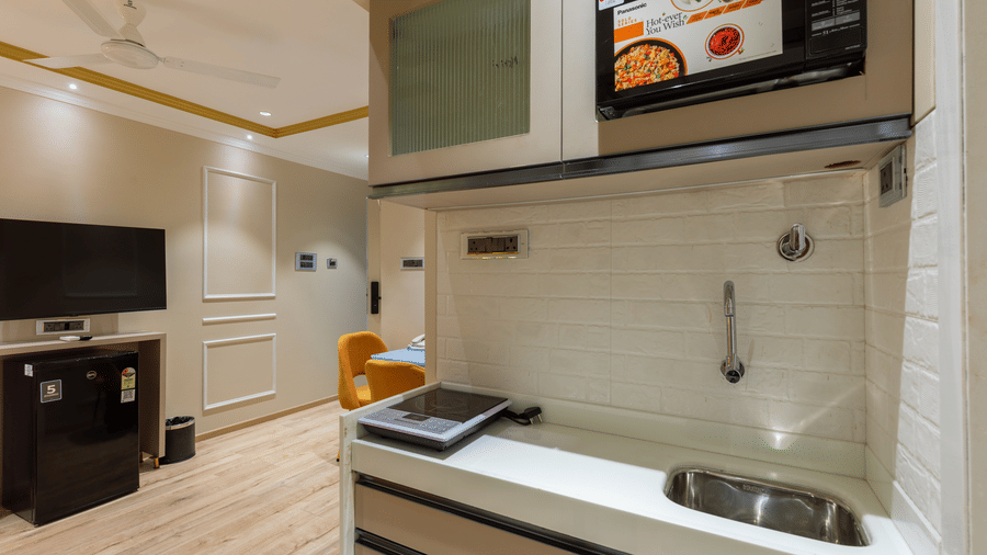 A well-equipped kitchenette featuring a microwave, sink, and flat-top stove - Home2 Residency, Mumbai Airport