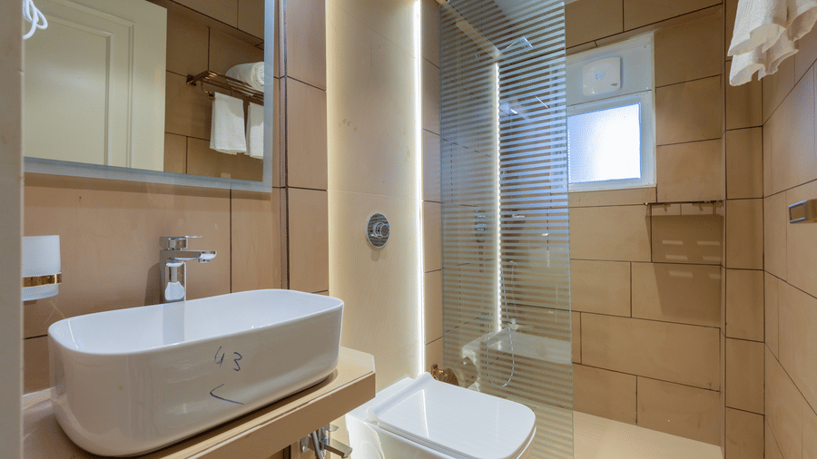 A clean, modern bathroom featuring a vessel sink, glass shower stall, and neutral tiling - Home2 Residency, Mumbai Airport