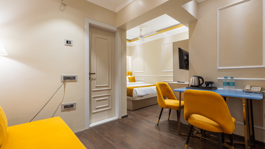 An open-concept room layout with yellow furniture accents, a dining nook, and a bedroom area - Home2 Residency, Mumbai Airport