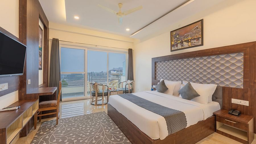 a double bed with a TV opposite it inside one of the rooms - Stone Wood Mountain Resort, Dharamshala - Dharamshala Place to Stay