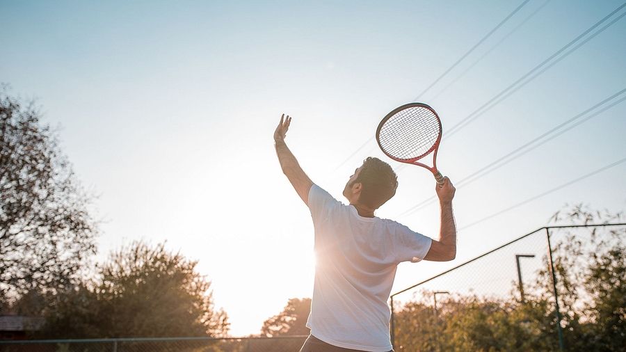 A back view of a person playing badminton on a sunny day | Karma Chalets