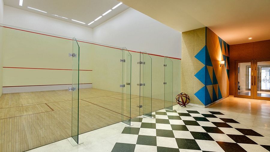 Modern indoor squash court with glass walls and checkered flooring | Karma Chalets