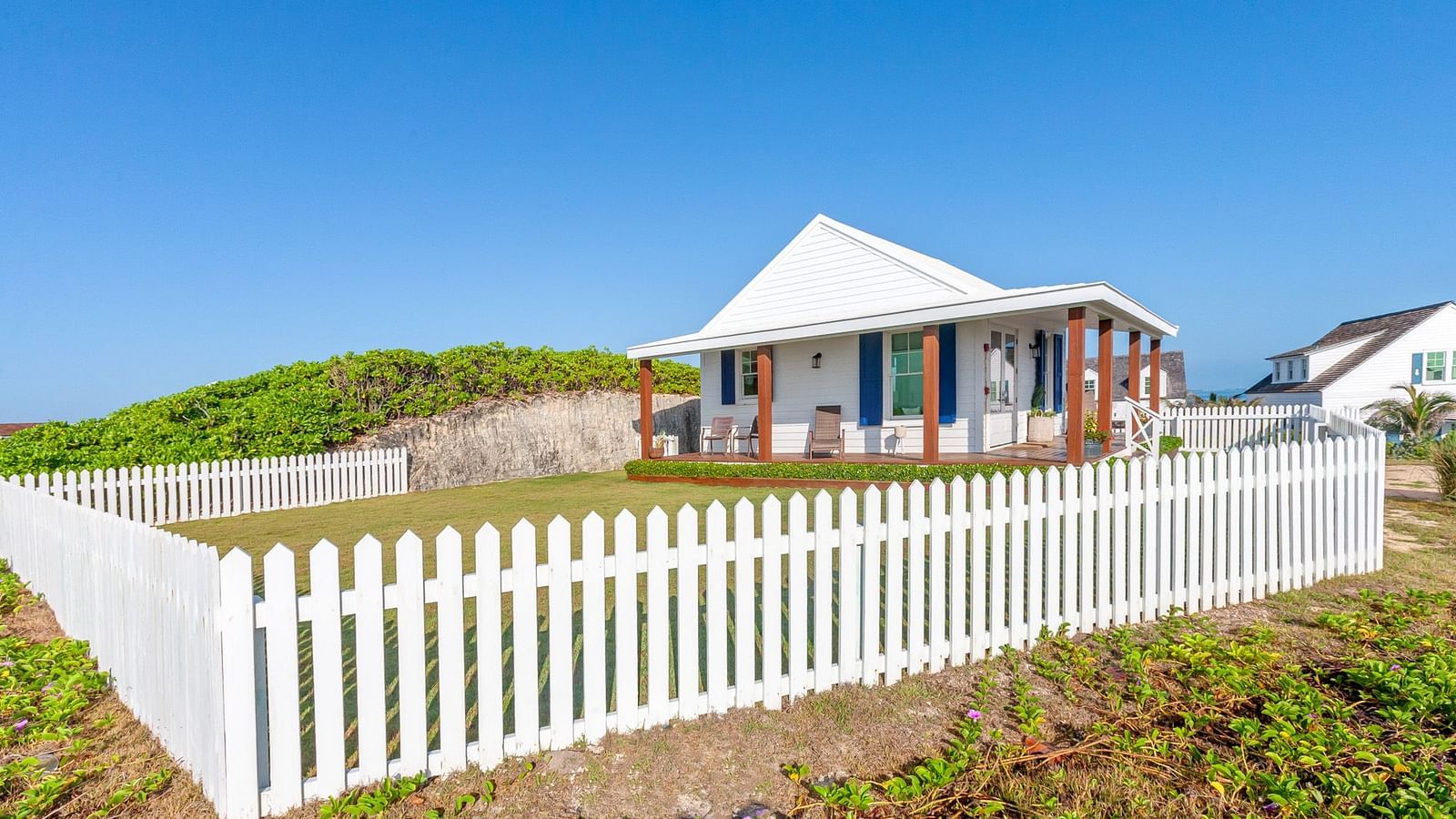 Side view of Hill Top Cottage at Abaco Inn with white fencing and natural surroundings.