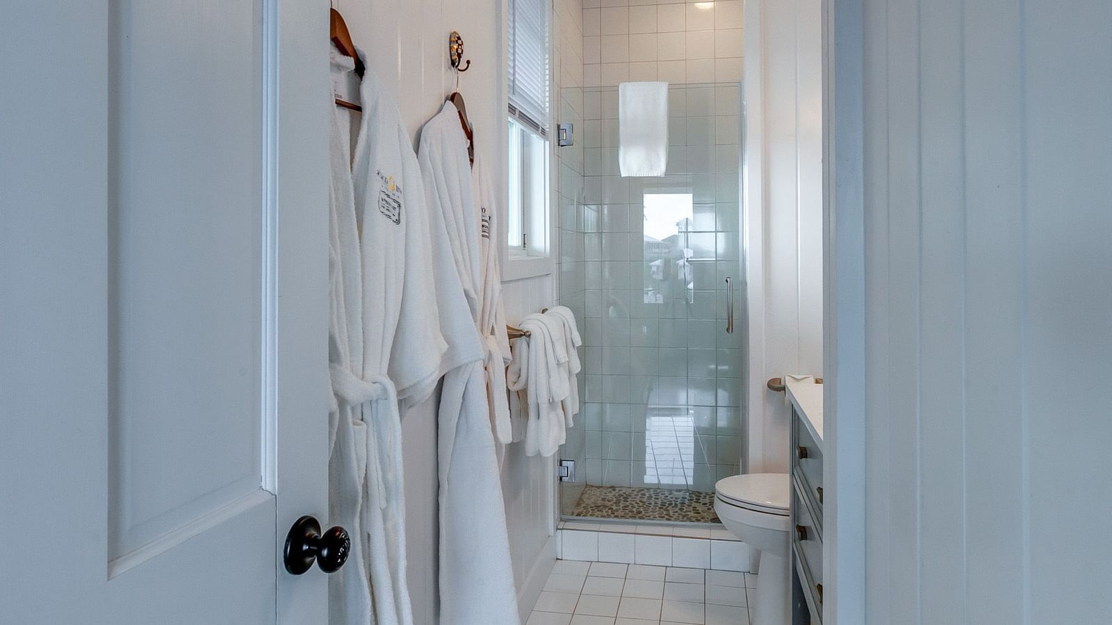 Bathroom view inside Hill Top Cottage at Abaco Inn with robes hanging on the door.