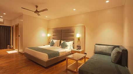 a double bed with a lounger next to it inside Pool view room - The Cindrella Hotel, Siliguri