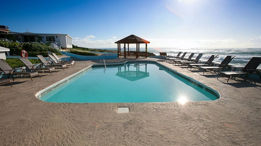 Swimming pool with sunbeds and ocean view in the distance | Abaco Inn
