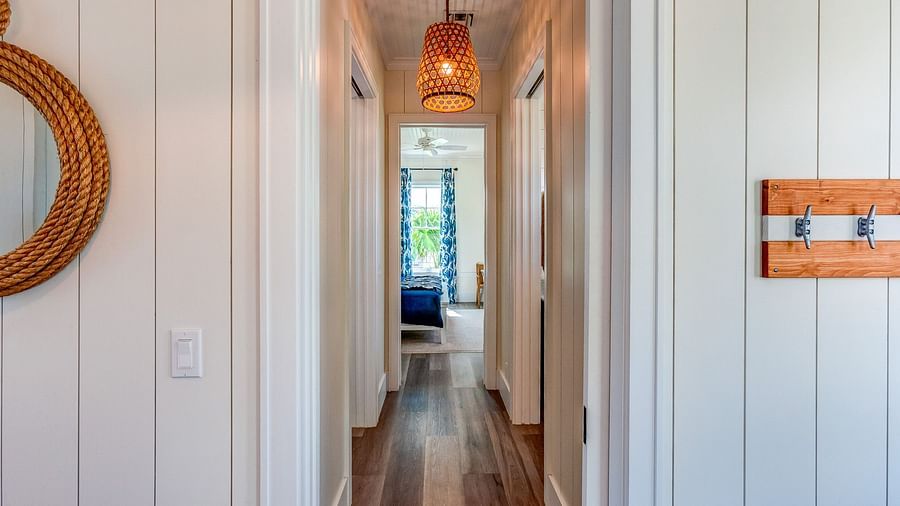 Hallway with wooden flooring, white panelled walls, and a hanging light fixture | Abaco Inn