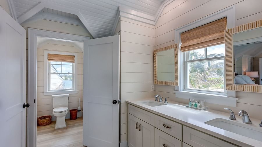 Bathroom with a vanity, white cabinets, and a glass-enclosed shower | Abaco Inn