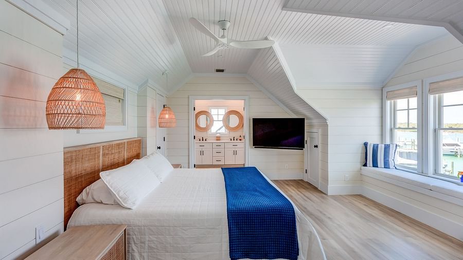 Bedroom with sloped ceiling, wooden furniture, and a TV | Abaco Inn