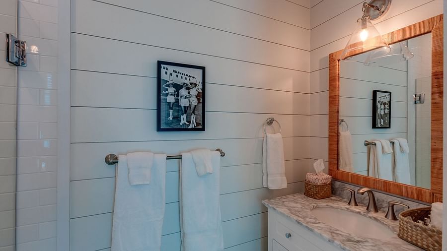 Bathroom with a mirror, wash basin, white towels, and framed artwork | Abaco Inn