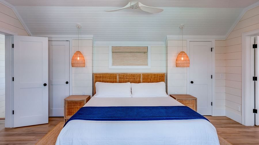 Bedroom with white walls, blue bed runner, and wooden accents | Abaco Inn