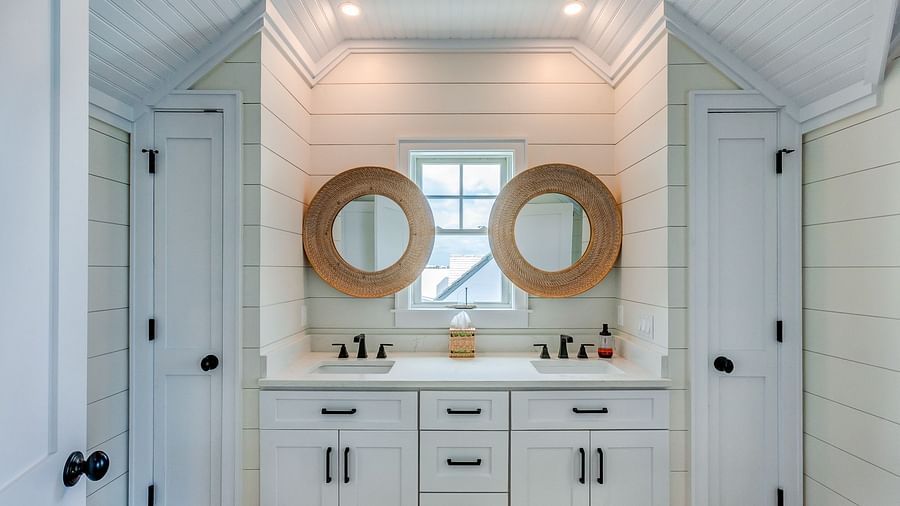White bathroom with double vanity sinks and circular mirrors | Abaco Inn