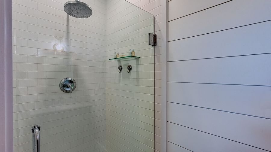 Glass-enclosed shower with white tiles and a rainfall showerhead | Abaco Inn