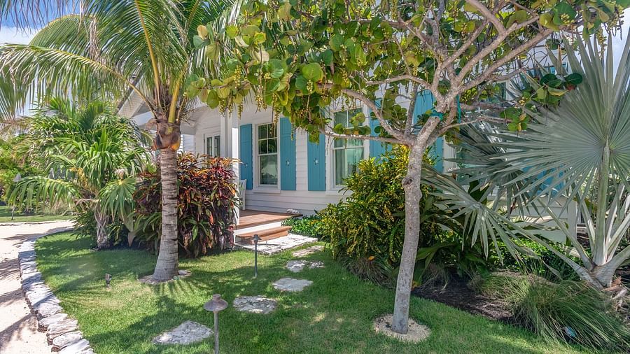 Garden with lush greenery, stone pathway, and an entrance to the cottage | Abaco Inn
