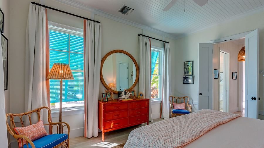 Bright bedroom with a large bed, wicker chair, and windows with natural light | Abaco Inn