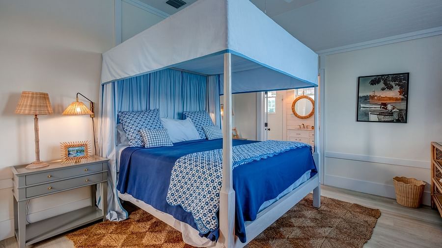 Bedroom with a blue canopy bed, wooden nightstand, and soft lighting | Abaco Inn