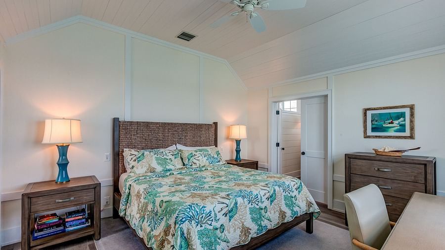 Bedroom with a patterned bedspread, wooden furniture, and a ceiling fan | Abaco Inn