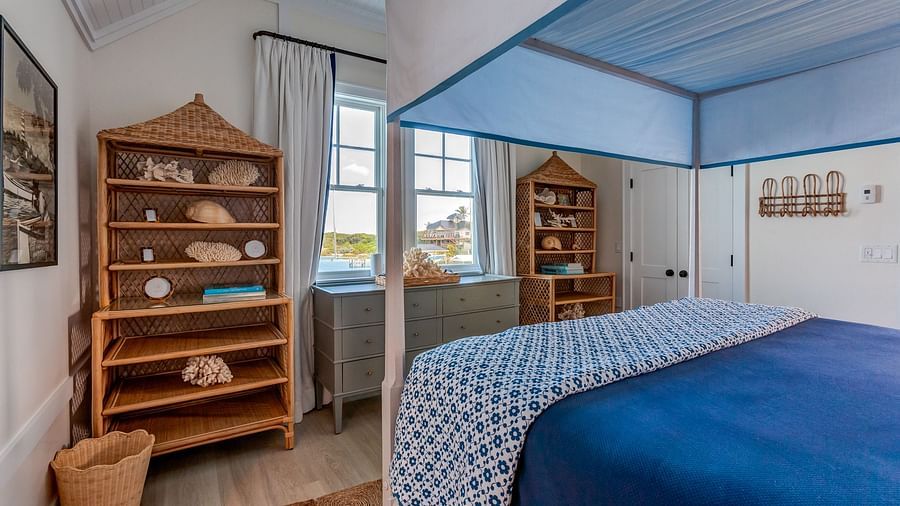 Bedroom with a blue canopy bed, wooden shelves, and ocean views | Abaco Inn