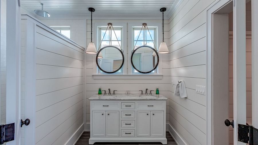 Double vanity bathroom with two round mirrors and a white countertop | Abaco Inn