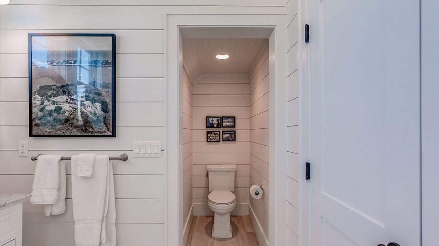 Bathroom view with white towels, framed artwork, and a toilet area | Abaco Inn