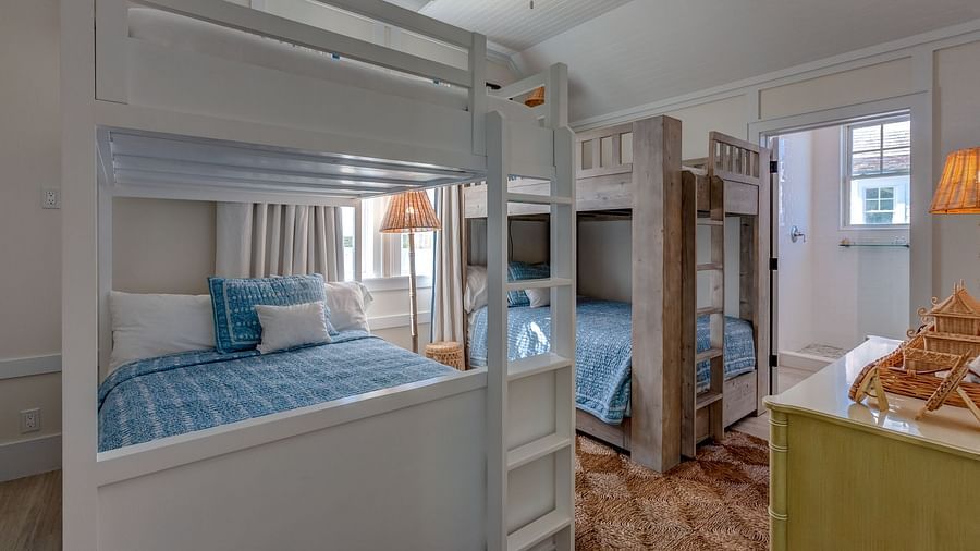 Room with white bunk beds, a green couch, and wooden flooring | Abaco Inn
