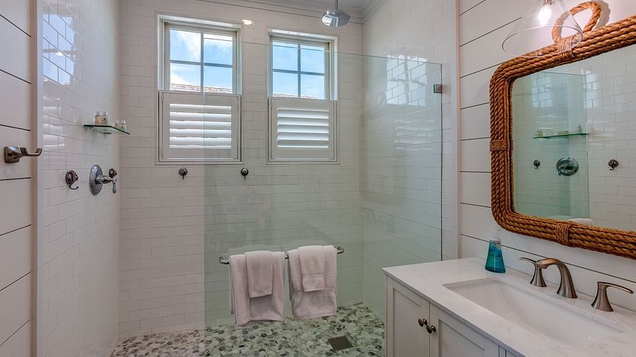Bathroom with a walk-in shower, white vanity, and two pink towels | Abaco Inn
