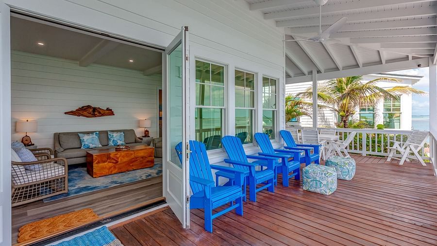 Lounge area opening onto a wooden deck with blue chairs and a sea view | Abaco Inn