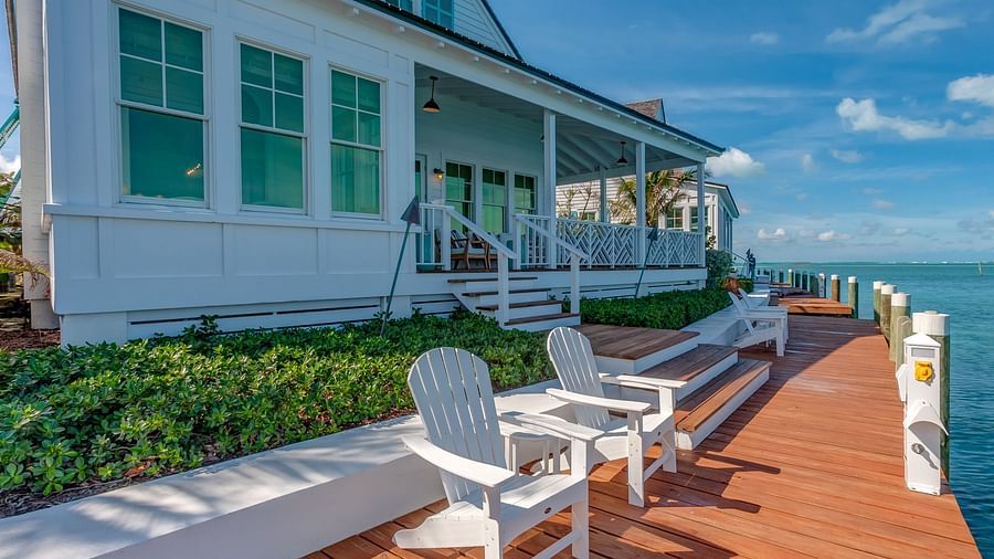 Oceanfront deck with white chairs overlooking the sea and greenery | Abaco Inn