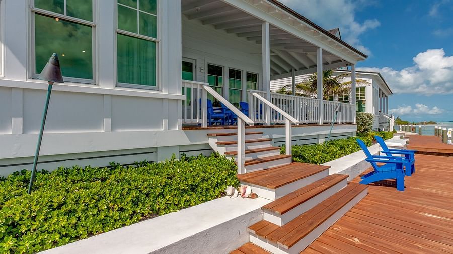 Waterfront deck with blue Adirondack chairs and a view of the calm sea | Abaco Inn