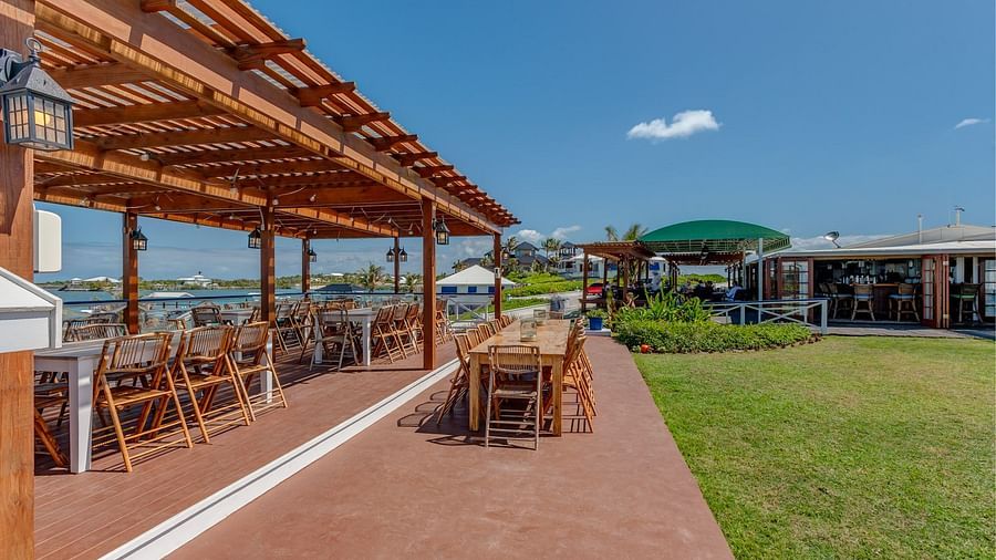 Dining patio with wooden tables and pergola | Abaco Inn