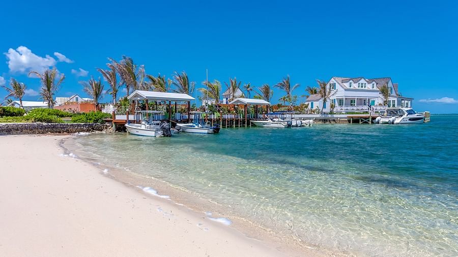 Sandy beach area with clear shallow water and buildings in view | Abaco Inn