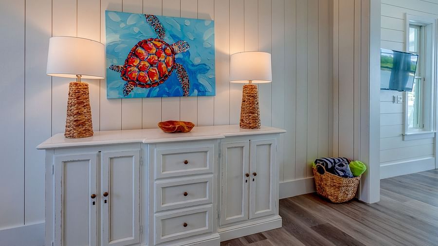 White sideboard with a colourful turtle artwork and two lamps | Abaco Inn