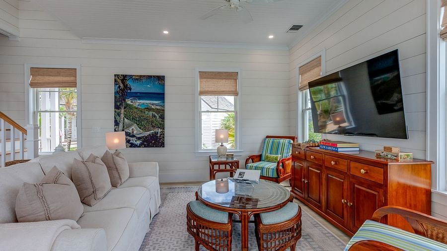 Living room with a sectional sofa, wooden furniture, and wall-mounted TV | Abaco Inn