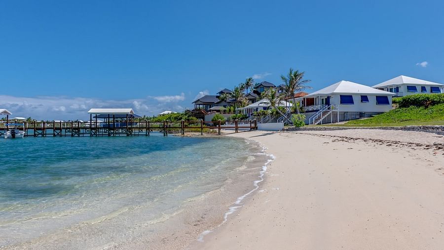 Sandy beach with gentle waves and buildings nearby | Abaco Inn