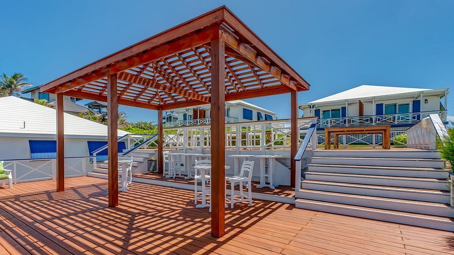 Wooden deck with pergola and chairs under clear sky | Abaco Inn