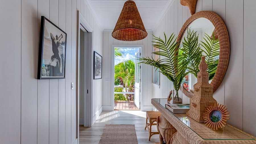 Bright hallway with a mirror, plants, and a woven pendant light | Abaco Inn