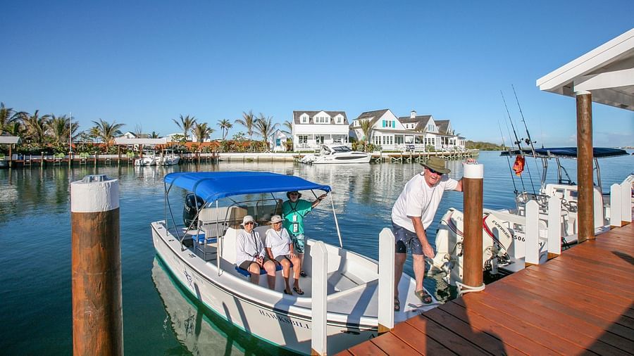 Docked boat by the boardwalk with buildings in the background | Abaco Inn