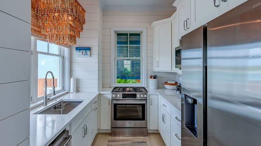 Modern kitchen with white cabinetry, stainless steel appliances, and a window view | Abaco Inn