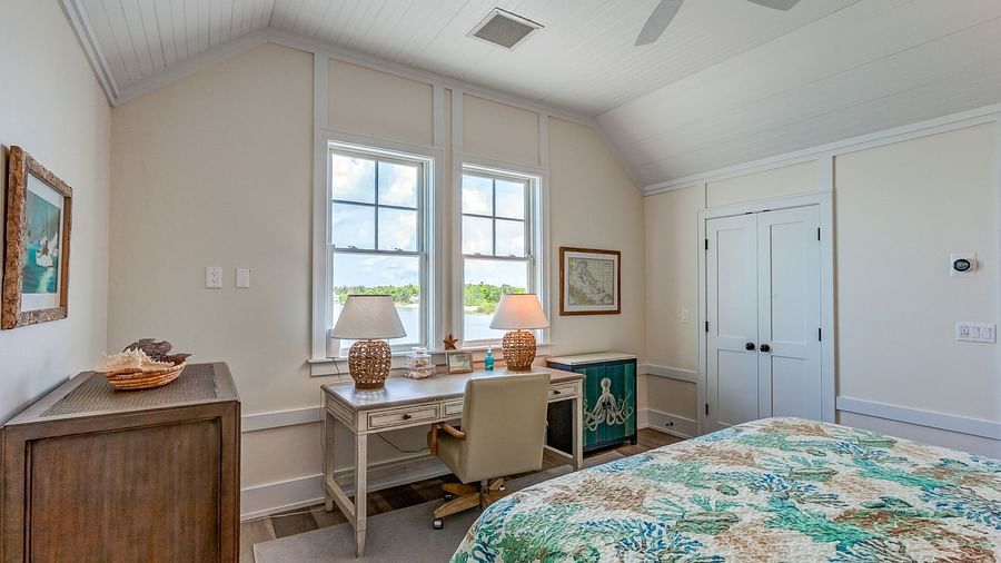 Bedroom with a floral bedspread, white walls, and a window letting in natural light | Abaco Inn