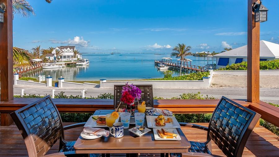 Dining setup on a patio overlooking boats and water | Abaco Inn